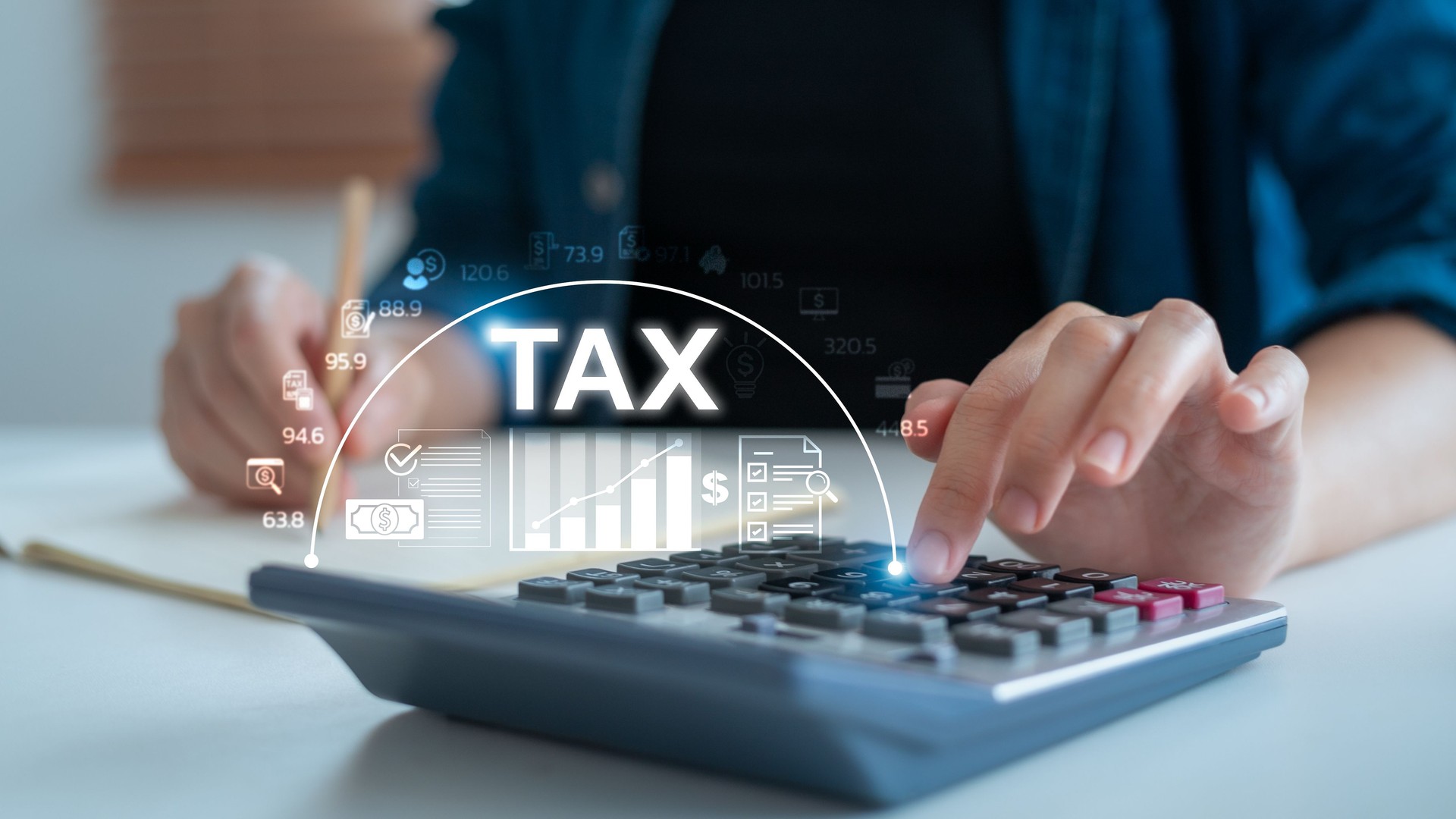 Close-up hand using calculator with TAX text and financial data icons. Concept of business tax planning, accounting analysis, and budget calculation.